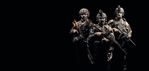 Three soldiers in uniform with a weapon in their hands are looking menacingly.