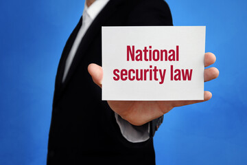 National security law. Lawyer holding a card in his hand. Text on the board presents term. Blue background. Law, justice, judgement