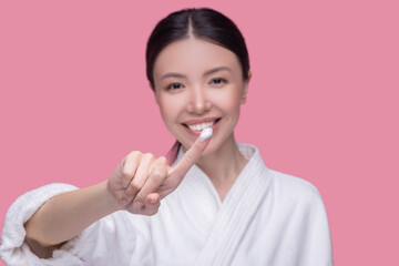 Smiling young woman applying novel facial cream