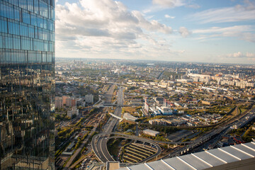 View of the city from the roof of a skyscraper on the right side of the wall of a mirror of another skyscraper on a sunny summer day