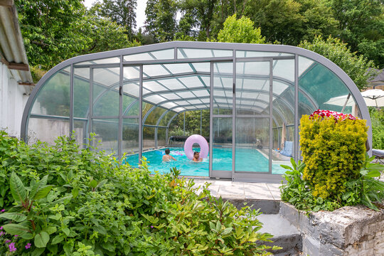 Swimming pool with a roof with kids playi,g inside oin a garden