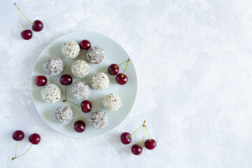 Homemade raw energy balls with cherry on the gray plate. Top view, close up, copy space on the gray background. Vegan sweets. Food with natural ingredients.