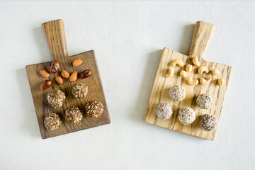 No bake sweets energy balls with hazelnuts, cashews, peanut butter and almond on the wooden boards on the white background. Organic snack. Top view, close up.