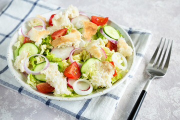 Salad fattoush. Healthy vegetarian food. Traditional Middle Eastern salad with toasted pita bread and vegetables in the white plate on the napkin. Close up.