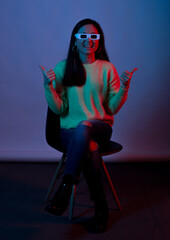 Dark purple photo of a young woman smiling at the camera  wearing 3d glasses for cinema showing like gesture