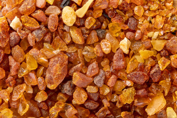 Raw small pieces of amber arranged on a wooden board. Precious pieces of old Baltic resin. Dark background.