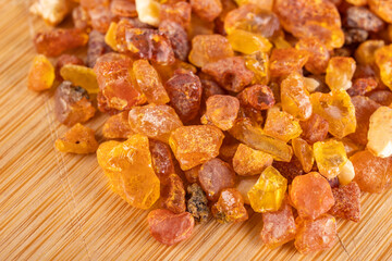 Raw small pieces of amber arranged on a wooden board. Precious pieces of old Baltic resin. Dark background.