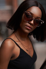 Closeup breast outdoor portrait of young beautiful african woman in black shirt. Trendy lifestyle girl in sunglasses looking at you