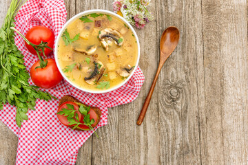 Vegetarian potato soup with mushrooms and croutons on a wooden background. Delicious vegetarian lunch with soup and bread with herbs and tomato.