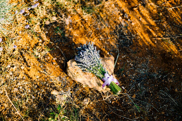 a bouquet of lavender with ribbons lying on the stone on the ground