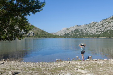 Wanderlust of a young woman, photographer and traveler. The woman is walking on the mountains and roads of the island of Majorca, the girl is wearing a hat and is taking photos. The woman is happy