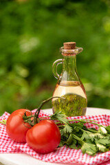 Olive oil with tomatoes and herbs in the fresh air. Summer salad ingredients.