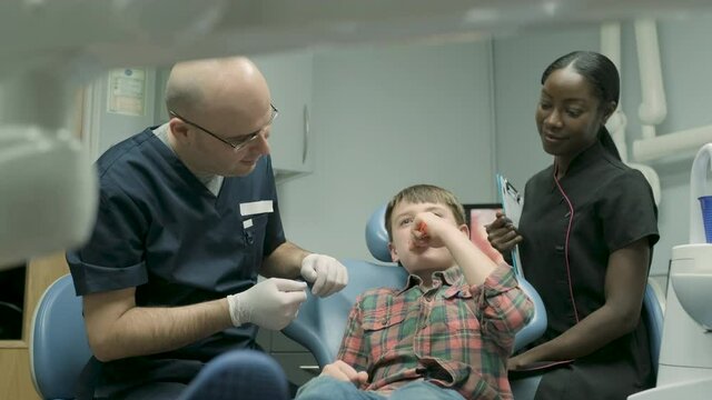 Dentist brushing one's tooth in dental surgery