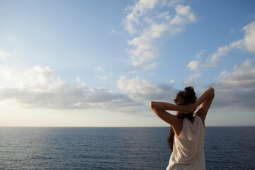 Portrait of a young woman in a seascape of the island of Majorca during the summer holidays. The woman is enjoying the views of the bay and the Mediterranean Sea at sunset