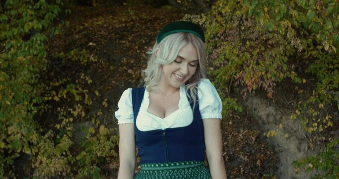 Happy blonde in thematic Slavic costume poses, smiles at camera on autumn nature