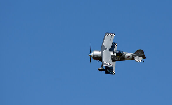 Pitts Model 12  stunt  byplane  with smoke trail and blue sky.