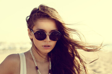 Portrait of beautiful girl in sunglasses at beach. Fashion style portrait