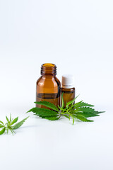 Medical, chemical theme background with cannabis leaves, oil bottle and young marijuana plant in a pot behind.