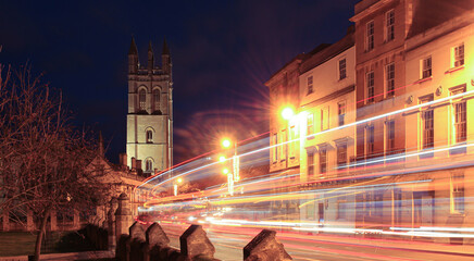 Streets of Oxford at night, floodlit tower with traffic trails in foreground