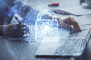 Double exposure of woman hands working on computer and lock hologram drawing. Security concept.
