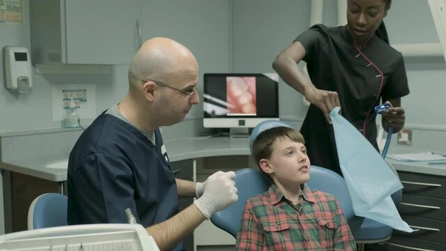Dentist and dental assistant preparing dental treatment for boy