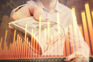 Multi exposure of financial graph drawing hologram and USA dollars bills and man hands. Analysis concept.