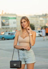 Hight fashion portrait of model posing outdoor in sunny day in stylish summer outfit.