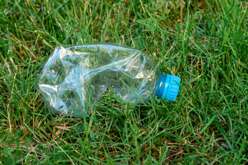 A plastic bottle lies in the grass. Environmental pollution concept.