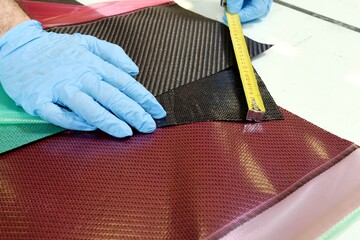 Professional worker with gloves manually realizes a component in real carbon fiber. Measurement and preparation of three different types of carbon fiber: plain, twill and satin.