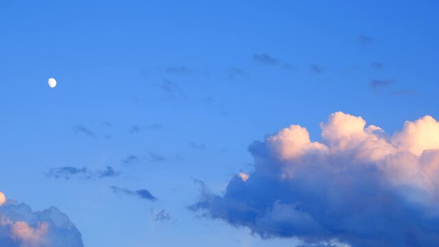 Cloduds - Cumulus congestus or towering cumulus - cover the moon on the blue sky, at the time of the setting sun and the beginning of the blue hour
