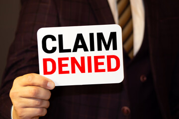 Businessman putting a card with text Claim Denied in the pocket