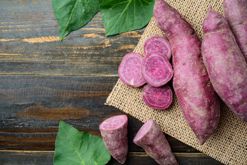 Raw purple sweet potatoes on wooden background