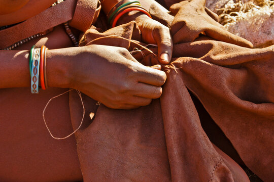 Hands of Himba woman sewing leather in a tribal village near Opuwo, Namibia