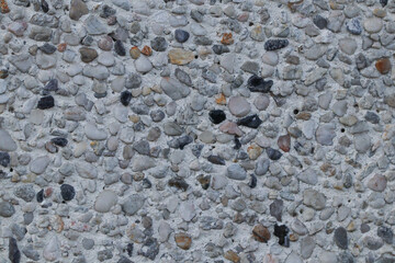 concrete texture of gray color with small colored and differently shaped pebbles, close-up.