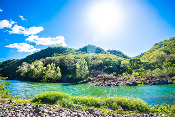 Beautiful Natural Landscape of Rocks, Water and Mountains. Wild nature scene. Light blue summer skies and calm aqua blue waters. Peaceful setting. Radiant Nature Background.