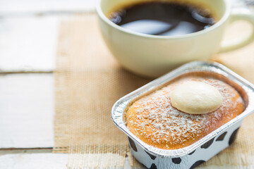 High angle views close up a cup of Hokkaido milk bread with topping cream on a wooden table with a cup of coffee blurred background.