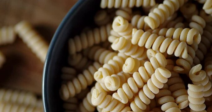 Bowl with dry pasta fusilli rotates slowly.