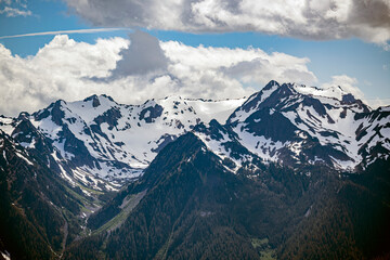 Snowcapped mountains rising up to blue and cloudy sky