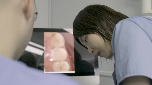 Dentist and dental assistant discussing treatment in front of computer