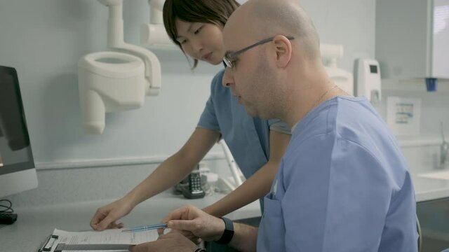 Dentist and dental assistant discussing in front of computer