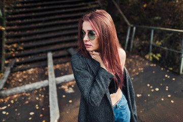 A girl of European appearance in a gray coat and glasses