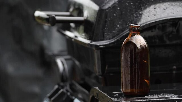Stubby beer bottle and barbecue in the pouring rain