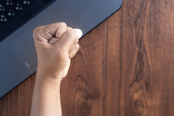 Close-up of an young woman's left hand in fist on wood table background.