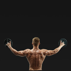 Bodybuilder lifting weights rising hands against black background. Fit and muscles sportsman...