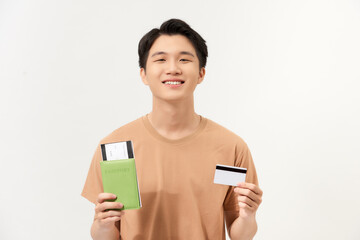 Portrait of a happy young man holding passport with tickets and showing plastic credit card isolated