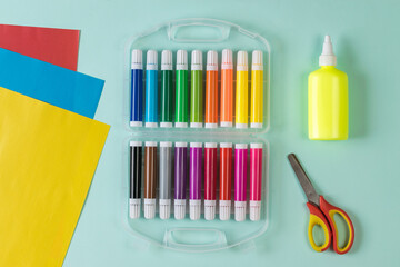 Fototapeta premium Scissors, glue, markers and colored paper on a light background.