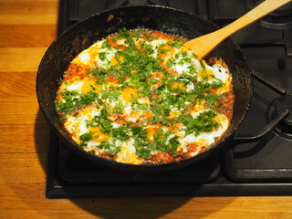 Image of fried eggs in a pan with tomatoes and herbs. Healthy summer natural food.