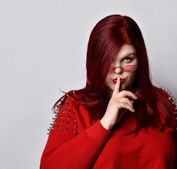 Fat ginger female in red spiked blouse and sunglasses. She is showing be quiet sign while posing...