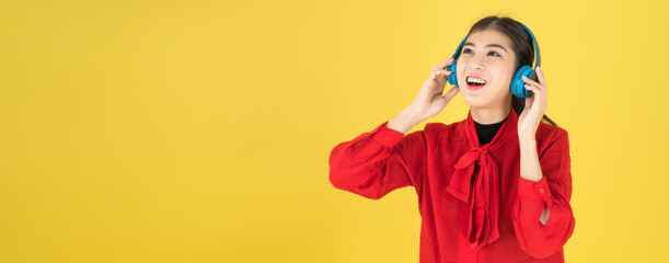 Banner of Asian women in the happy mood put the wireless headphone with red dress. listening music from Mobile or studying E-leanning