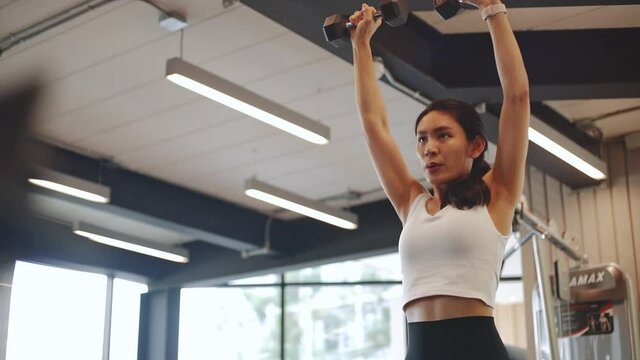 Young beautiful woman in sportswear working out with machine in gym	
